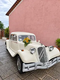 L'auto d'epoca con un mazzo di girasoli, davanti a un muro rosa