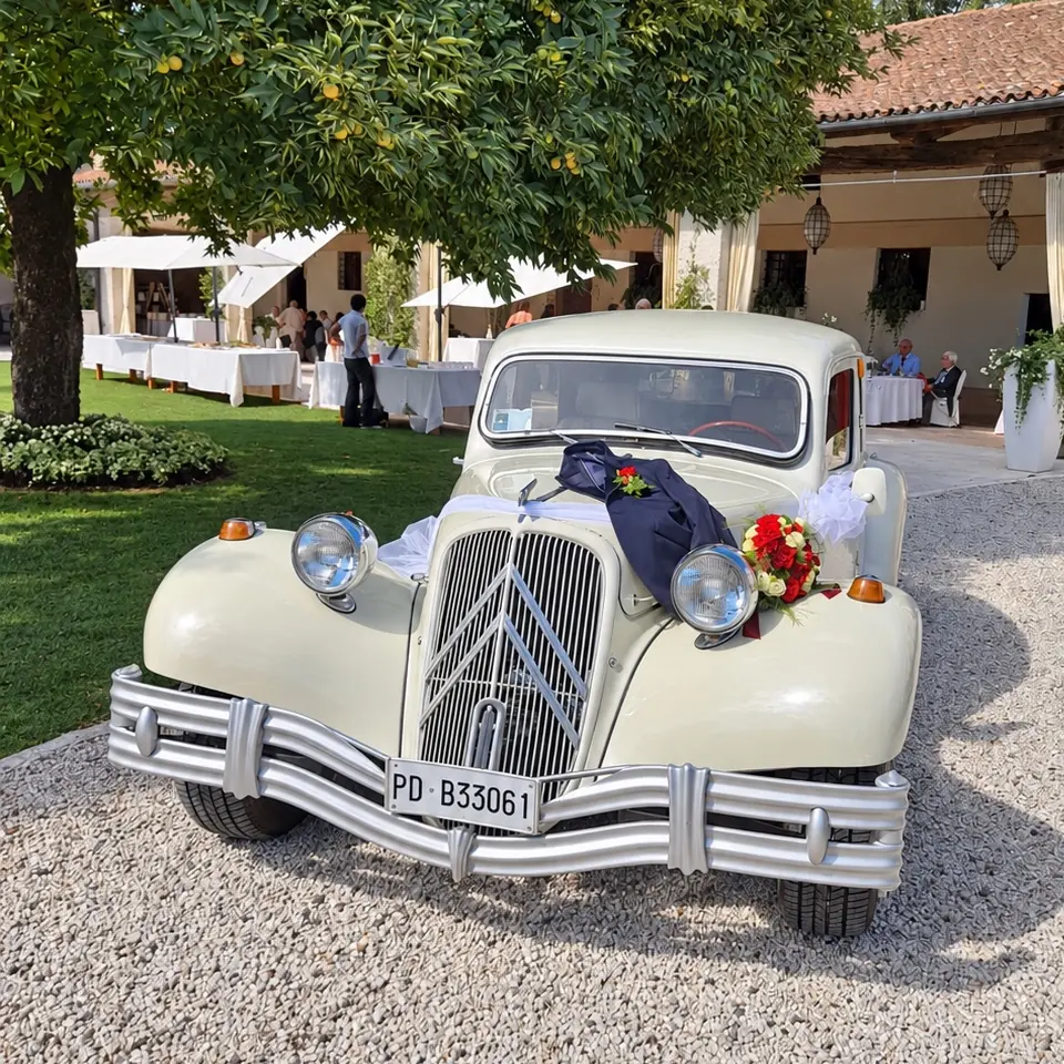 L'auto d'epoca color avorio del 1953, addobbata con fiori e nastri, davanti a una villa per un matrimonio