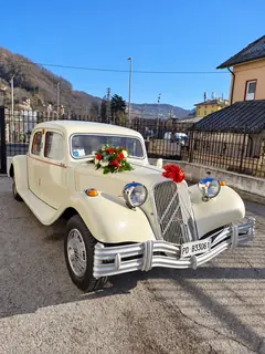 L'auto d'epoca con un mazzo di fiori rossi sul cofano, in paese